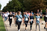 Gruppe von Menschen in Sportkleidung mit Startnummern, die auf einem Weg in einem Park gehen